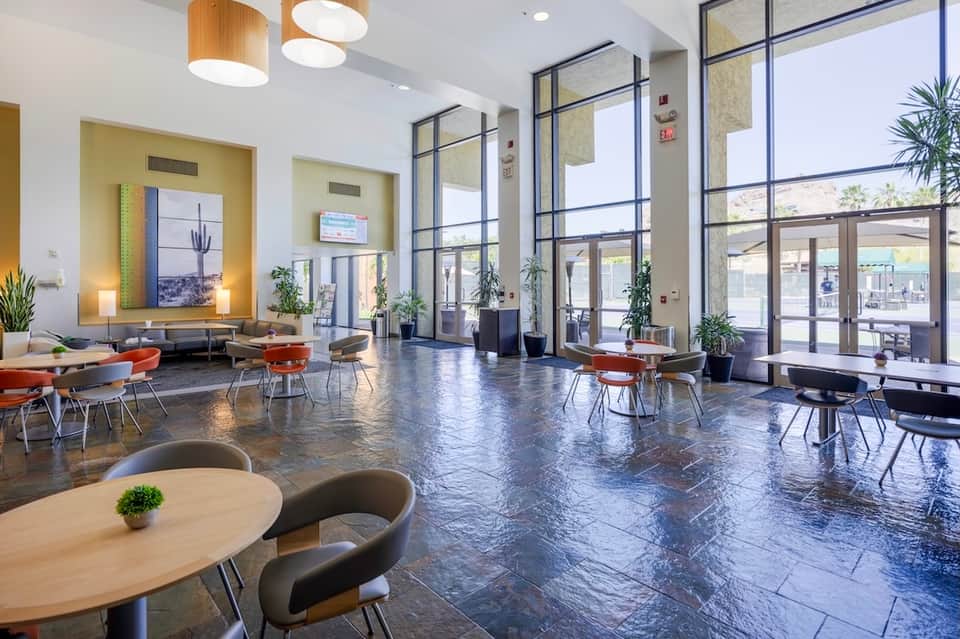 Modern hotel lobby with polished floor, contemporary seating, large windows, and yellow accent wall