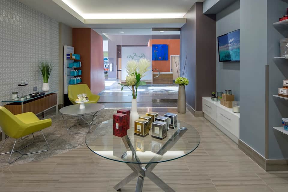 Modern hotel lobby with yellow chairs, glass table, colorful accent walls, and bright natural light
