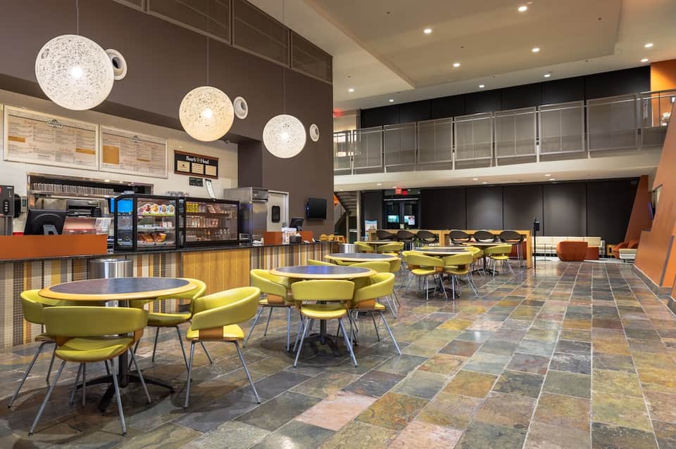 Hotel lobby café with lime green chairs, pendant lights, and service counter