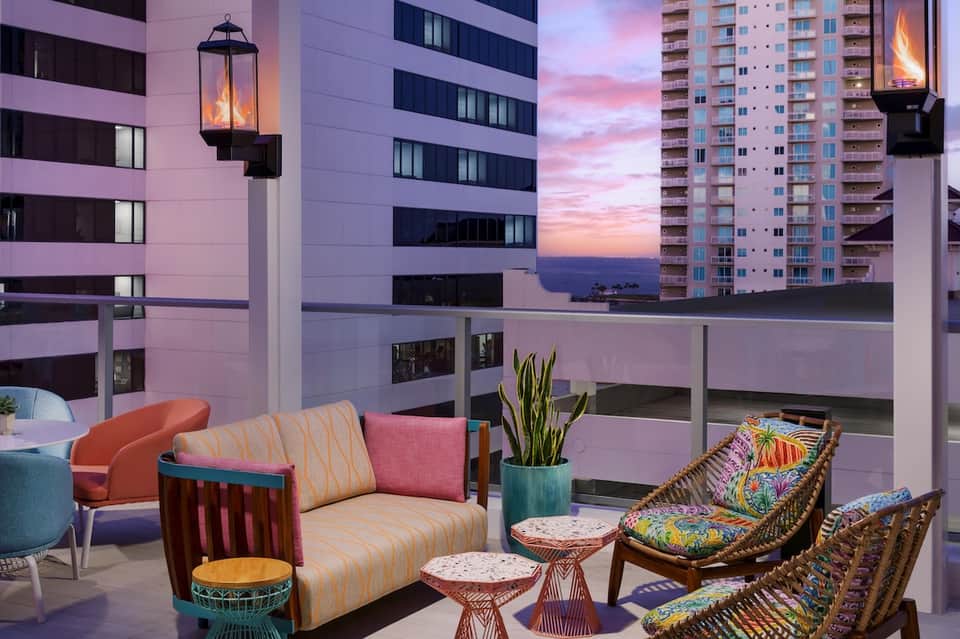 Modern resort lounge with colorful seating, sunset ocean views, and contemporary furnishings at dusk
