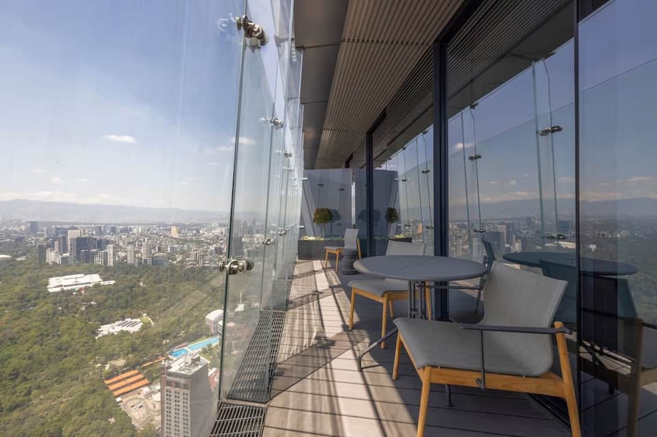 High-rise balcony with glass railings overlooking city skyline and park landscape