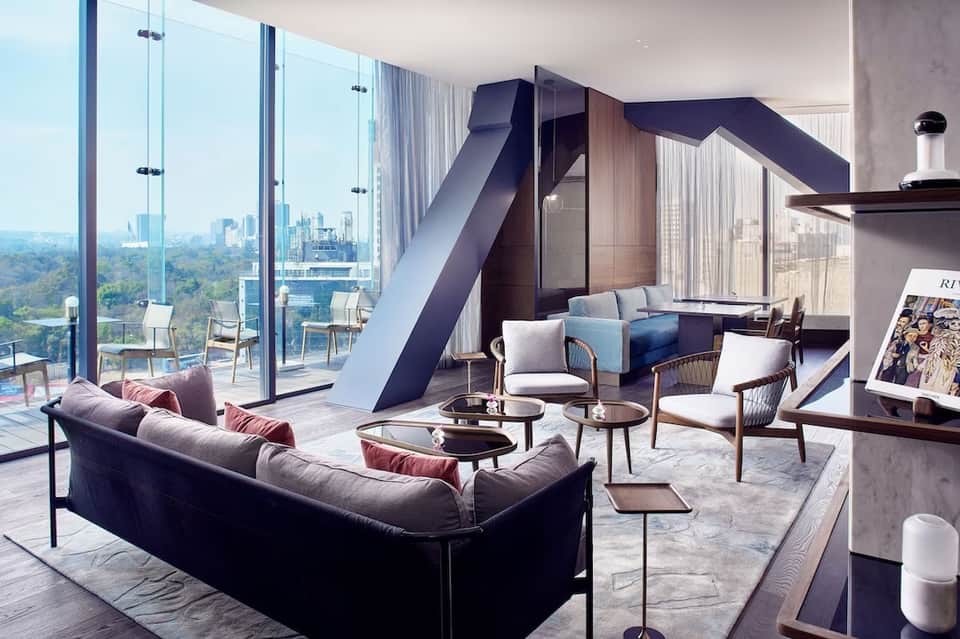 Luxury penthouse lounge with floor-to-ceiling windows, city skyline view, modern seating, and architectural design elements.