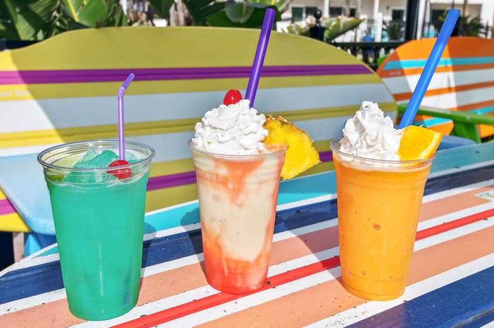 Colorful tropical cocktails with whipped cream and fruit garnishes