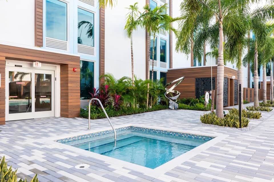 Contemporary spa hot tub on paved deck with tropical palm trees and modern architecture