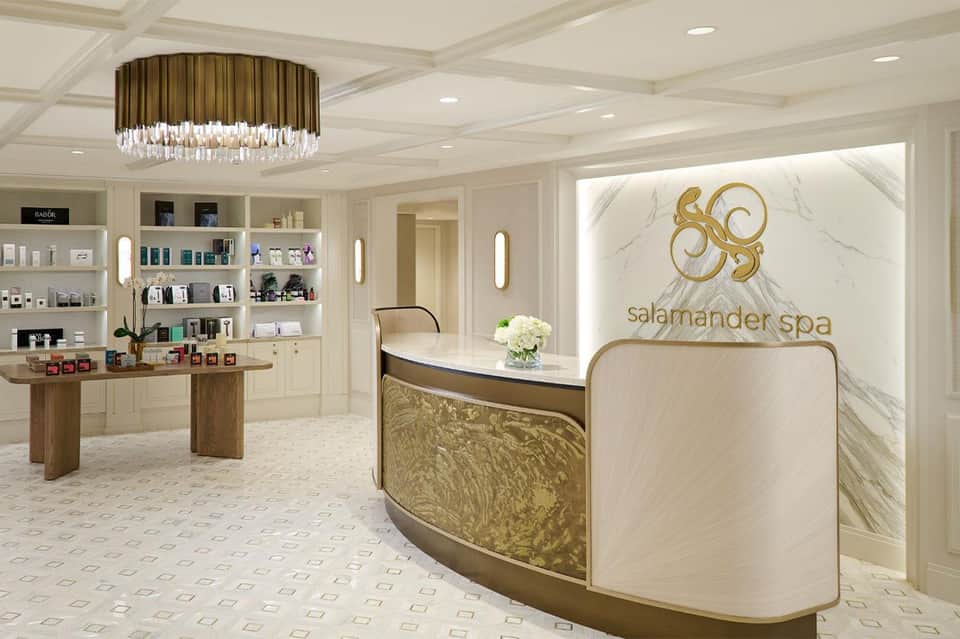 Luxury spa reception area with marble walls, gold accents, and upscale product displays