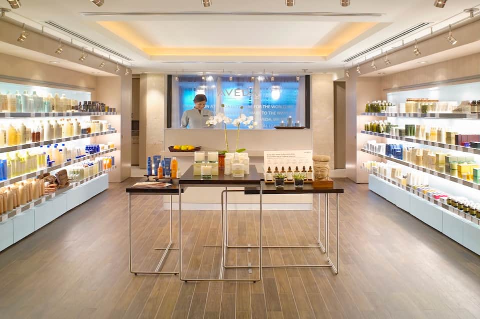 Modern spa retail boutique with illuminated product shelves, central display counter, and bright lighting
