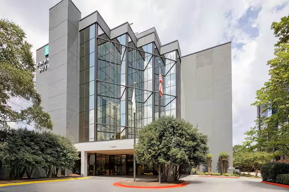 Contemporary hotel entrance with tall glass windows, geometric facade, modern signage, and landscaping