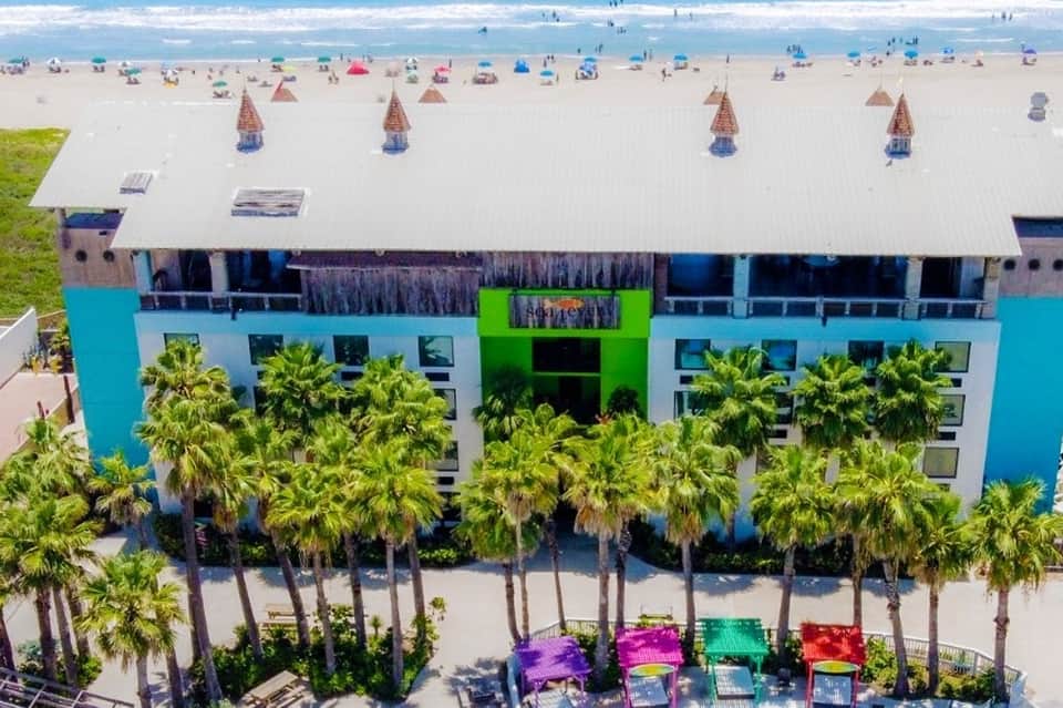 Beachfront hotel with colorful beach umbrellas and cabanas on sandy shore with ocean waves