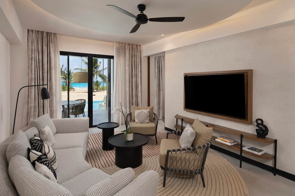 Luxury resort suite with ocean view, modern furnishings, and sliding glass doors