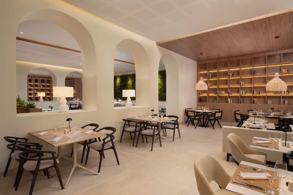 Contemporary restaurant interior with white archways, wood shelving, modern lighting, and minimalist dining tables