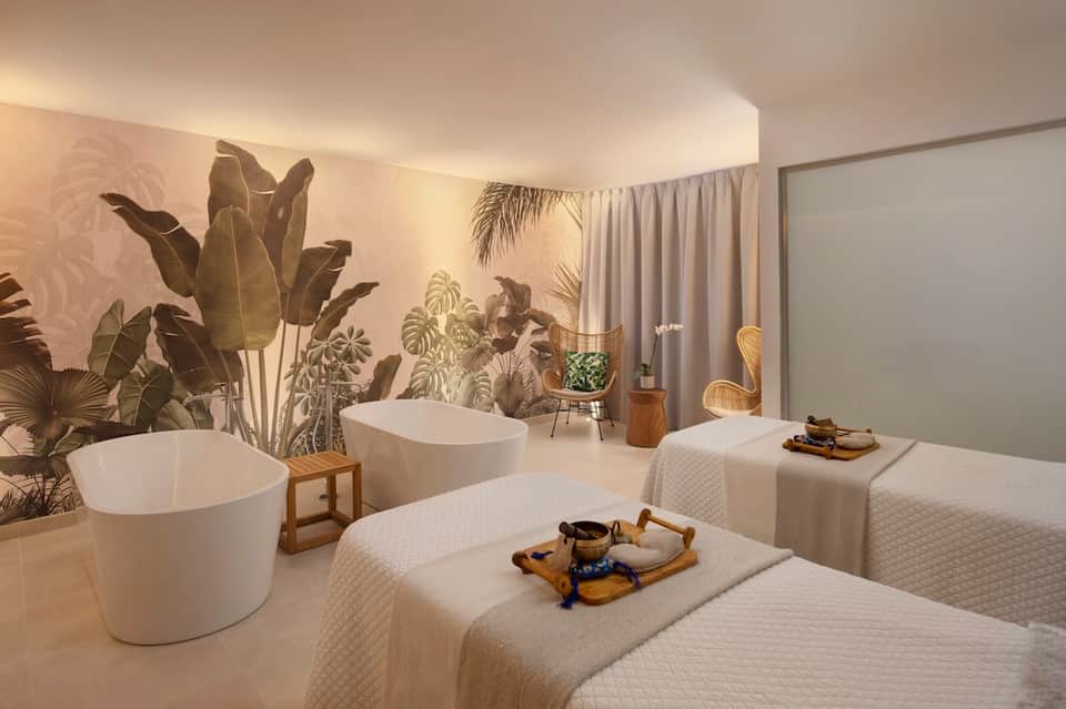 Contemporary spa treatment room with freestanding white tubs and botanical wall mural