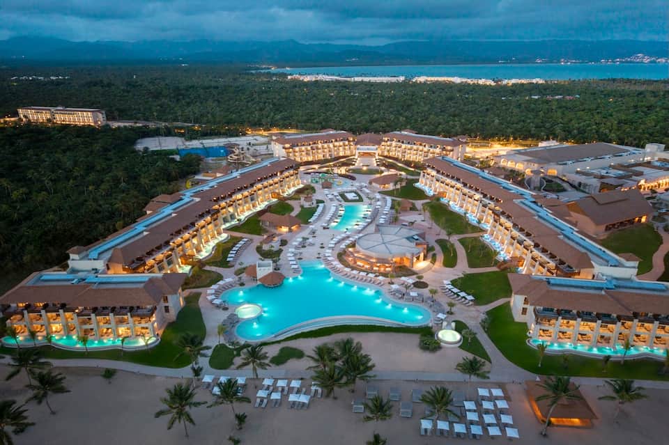 Aerial view of large all-inclusive resort with illuminated pools and tropical surroundings