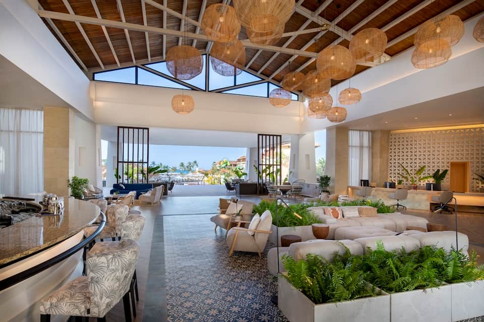 Grand hotel lobby with woven pendant lights, high ceilings, lounge seating, and waterfront views