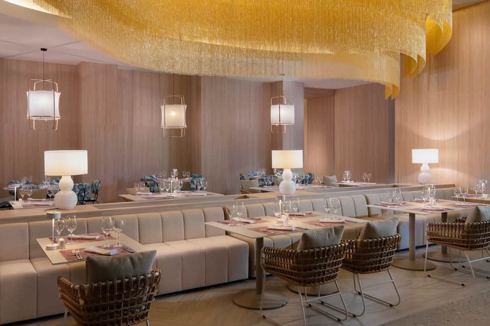 Elegant dining room with gold ceiling, pendant lighting, and upholstered seating