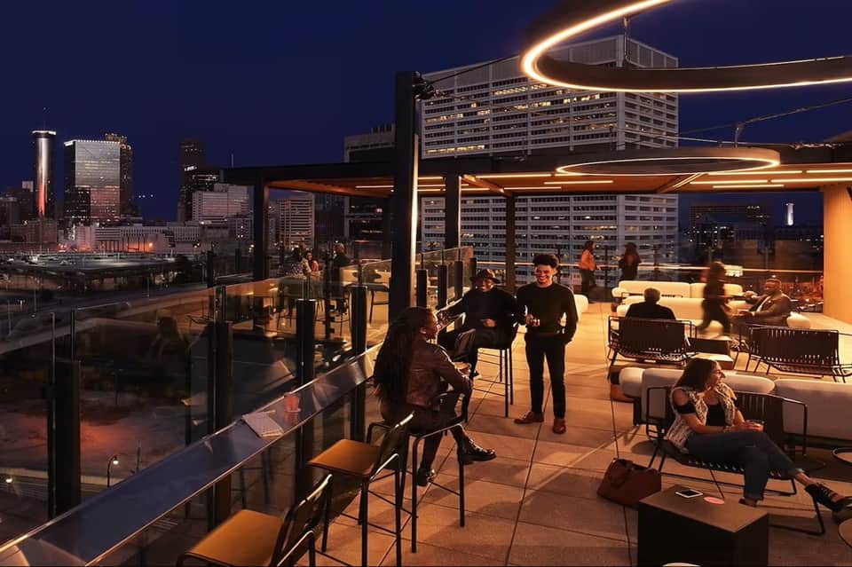 Urban rooftop lounge at night with city skyline views, lounge seating, and LED lighting