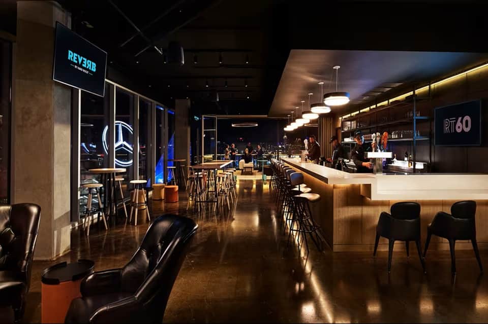 Contemporary hotel bar and lounge with modern furnishings, ambient lighting, and service counter