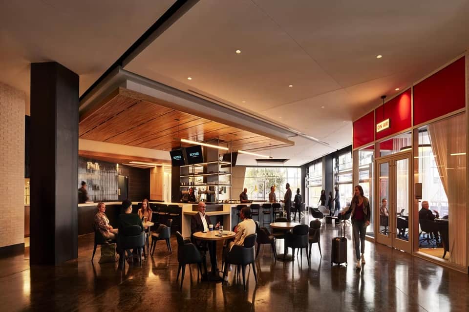 Contemporary hotel lobby and lounge with mixed seating, wooden ceiling details, and red accent wall