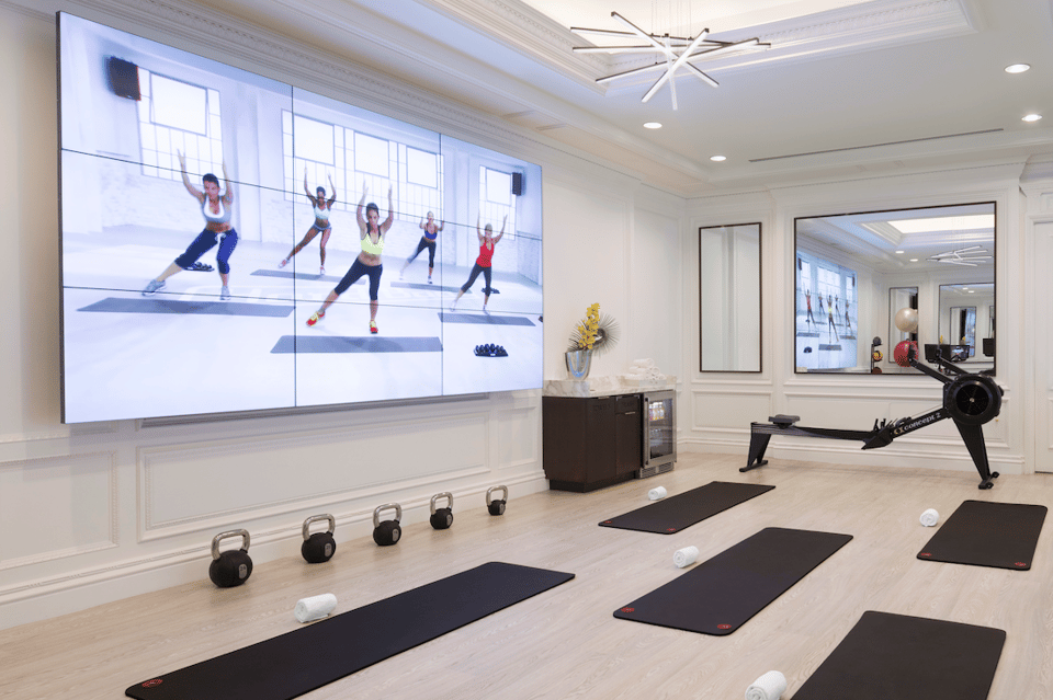 State-of-the-art fitness center with large video screen, exercise equipment, rowing machine, and white ceiling