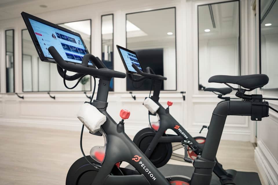 Fitness center with Peloton bikes equipped with digital screens and mirrored walls