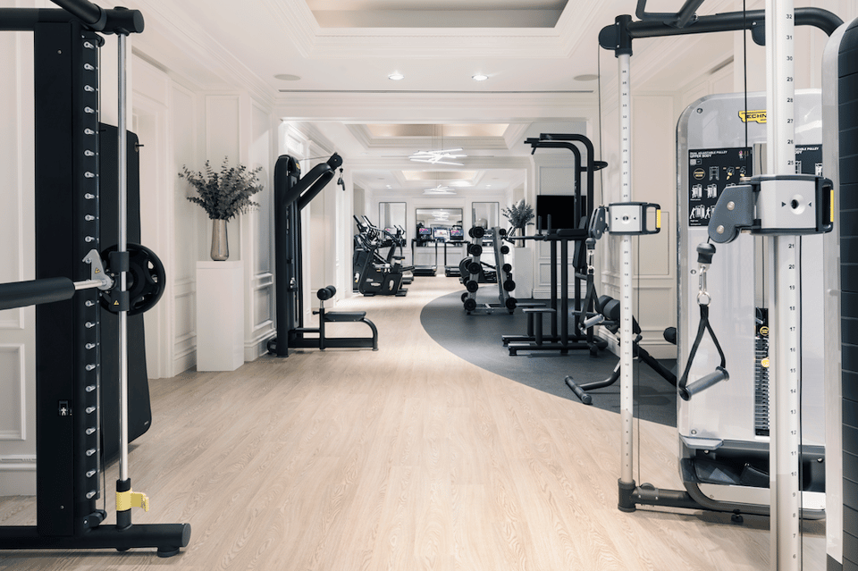 Bright fitness center with cardio equipment, weights, mirrors, and botanical decor