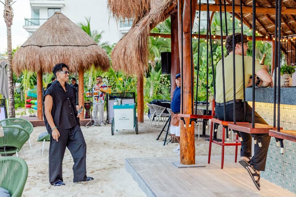 Beachfront casual dining area with thatched-roof palapas and tropical vegetation