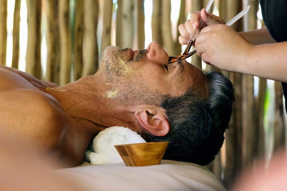 Barber trimming client's beard during professional grooming service indoors