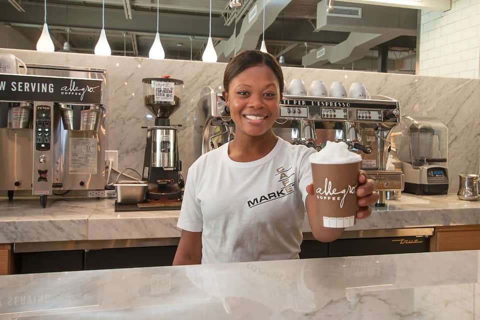 Hotel barista serving specialty coffee at modern marble counter with espresso machines