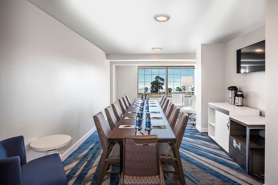 Contemporary conference room with long dining table, windows, and water views