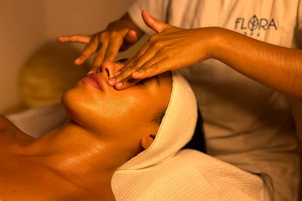 Spa massage therapist performing facial treatment on client at wellness center