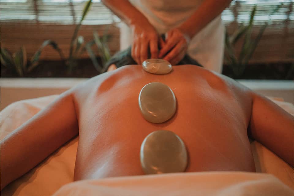 Close-up of spa massage stones placed on client's back during wellness treatment
