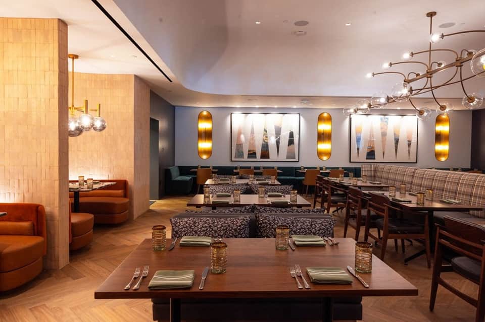 Elegant restaurant dining room with wood accents, artistic wall displays, and lounge seating