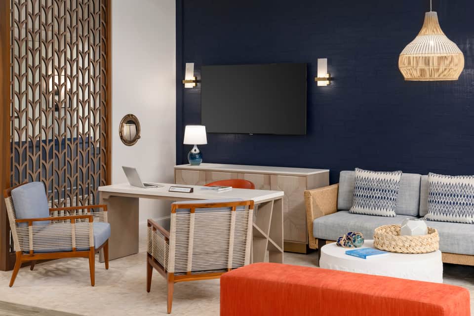 Modern hotel suite interior with navy accent wall, desk, sofa, and contemporary furnishings