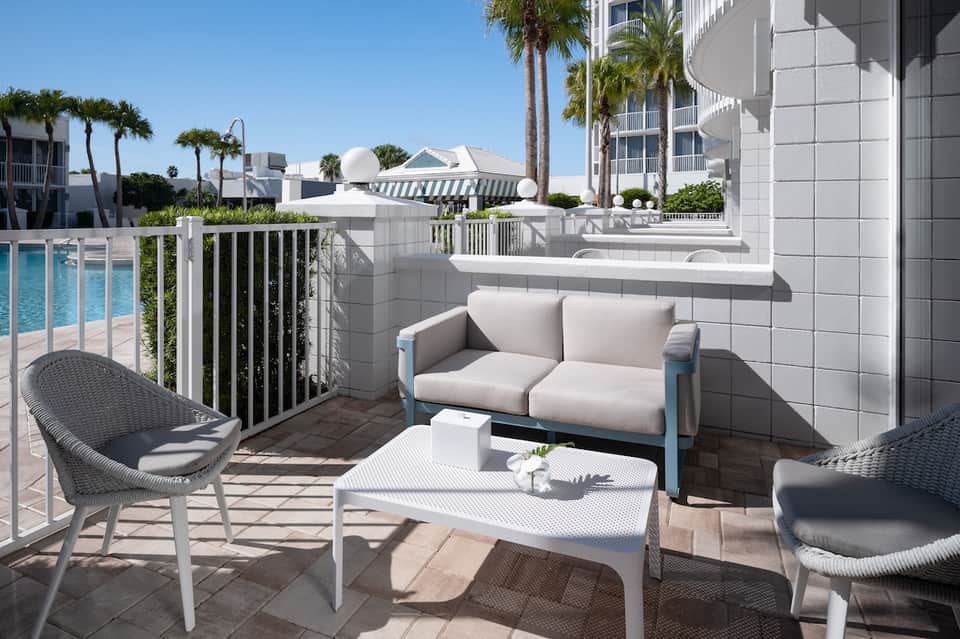 Beachfront hotel balcony with comfortable seating, ocean view, and palm trees