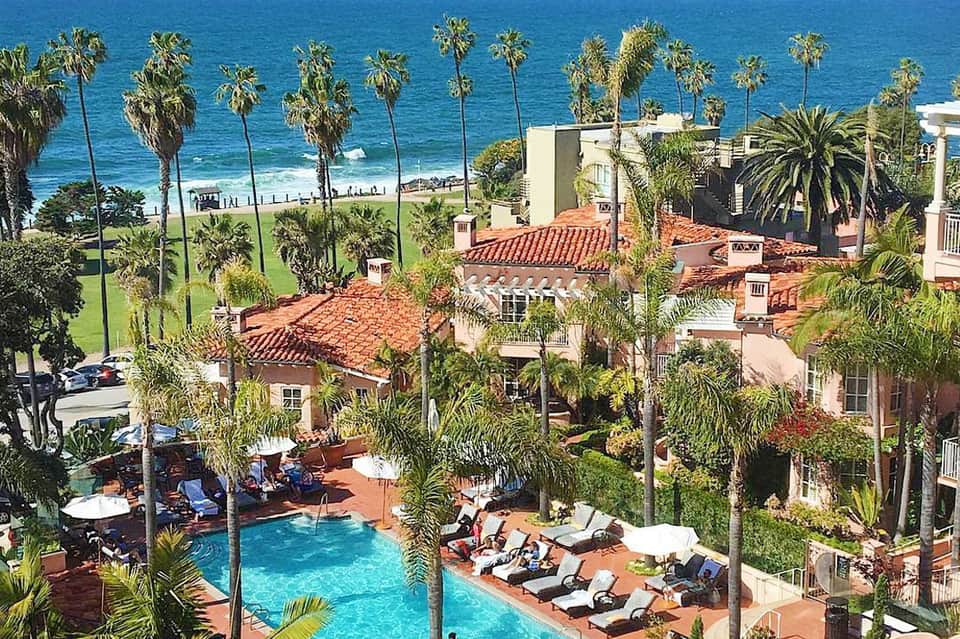Beachfront resort with Spanish-style architecture, palm trees, pool, and ocean view