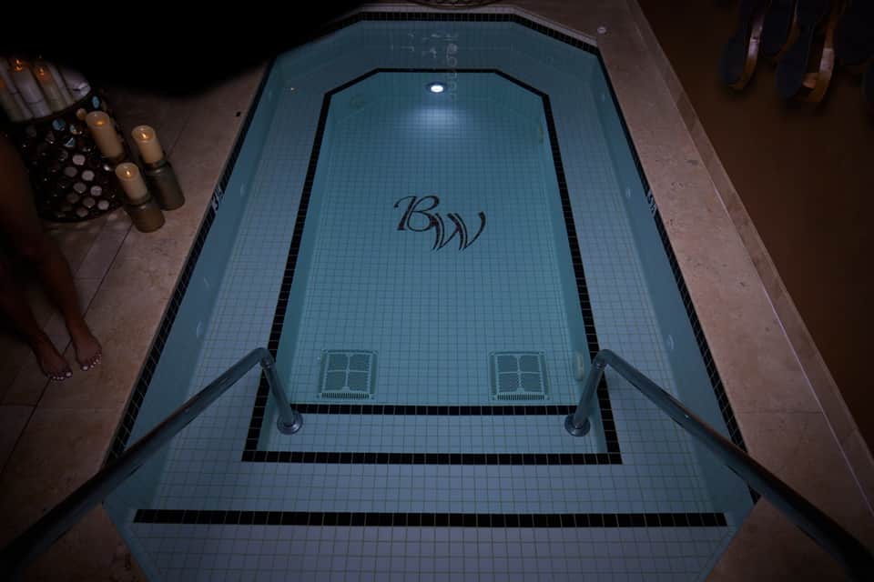 Indoor spa pool with blue tile, logo branding, and ambient lighting