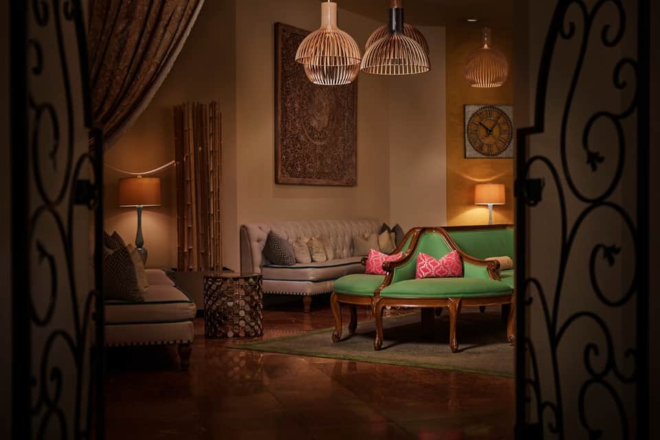 Elegant lounge with green velvet settee, warm lighting, and decorative pendant lamps