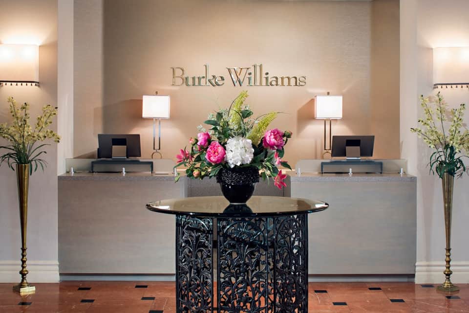 Burke Williams spa reception desk with pink flowers and elegant dual check-in counters