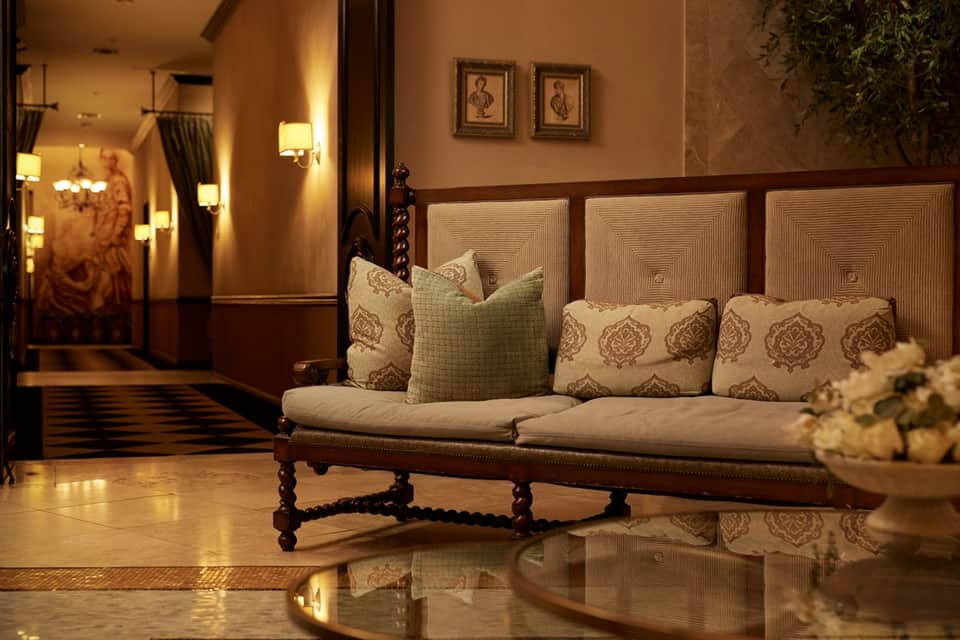 Elegant lobby with decorative sofa, warm lighting, marble floors, and classical artwork