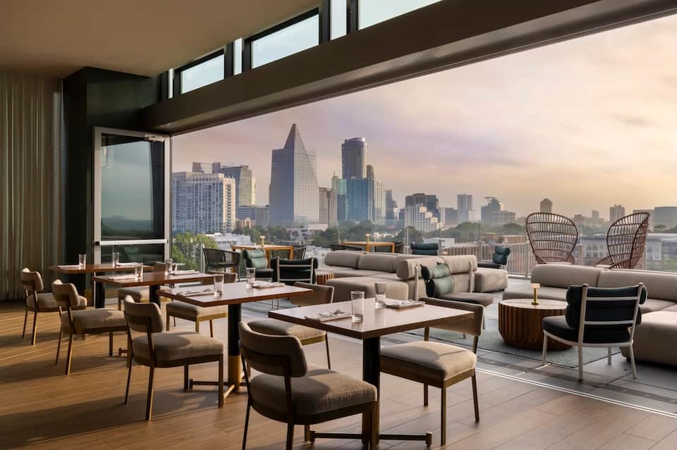 Luxury penthouse lounge with floor-to-ceiling windows showcasing expansive city skyline views and contemporary furnishings