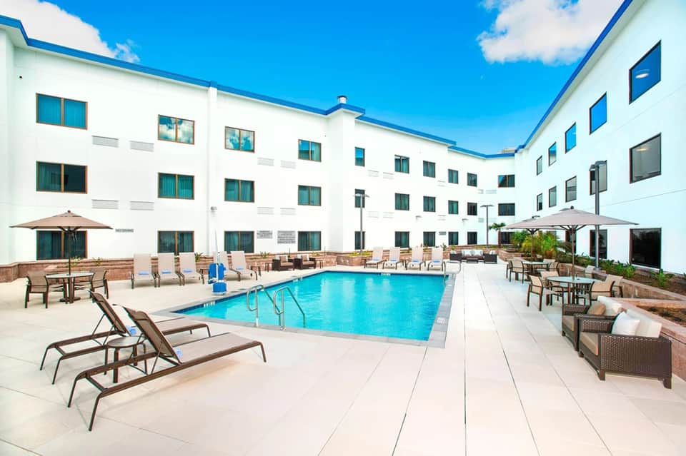Modern courtyard pool surrounded by white hotel building with blue roof accent