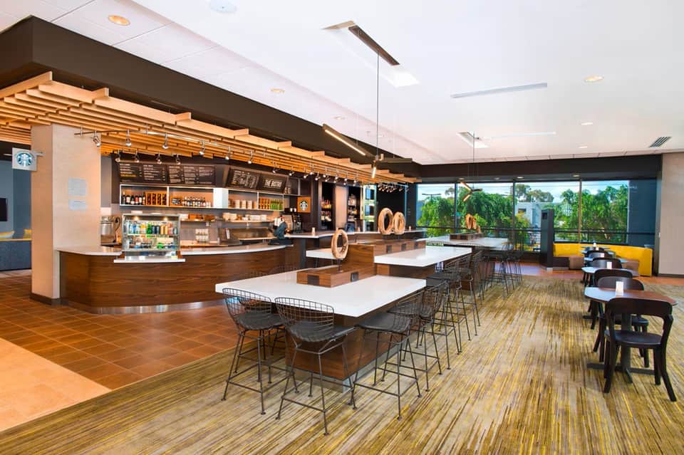 Modern café lounge with Starbucks counter, high seating, and floor-to-ceiling windows