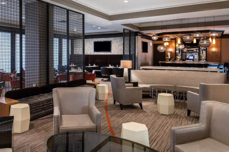 Upscale hotel lounge with modern furnishings, bar counter, pendant lighting, and decorative screens