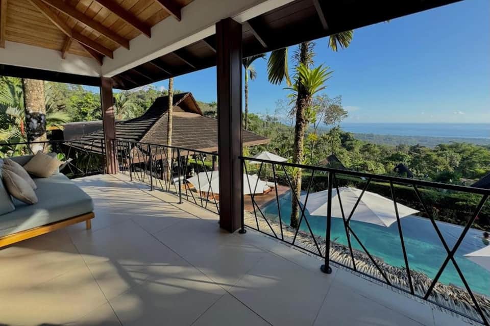 Elevated deck overlooking lush tropical landscape and ocean horizon with lounging areas