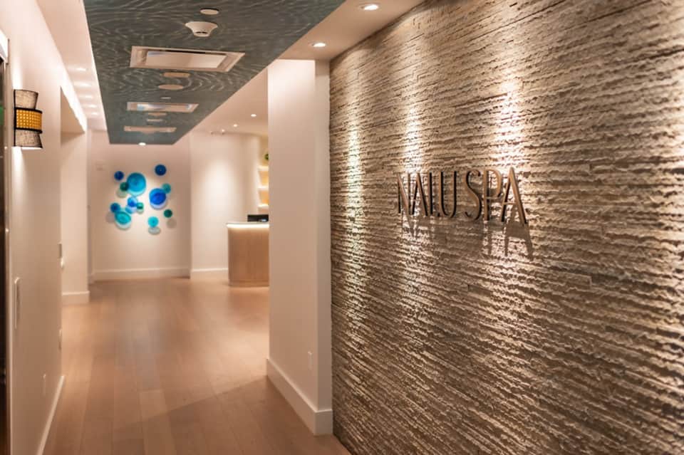 Modern spa entrance hallway with stone accent wall, signage, and contemporary lighting