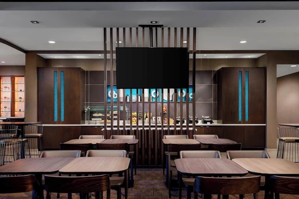 Modern hotel restaurant interior with dark wood design, blue accent lighting, and table seating