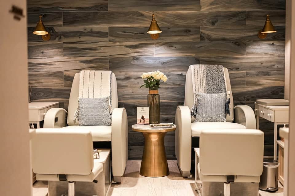 Spa treatment room with two massage chairs, wood accent wall, and brass pendant lighting