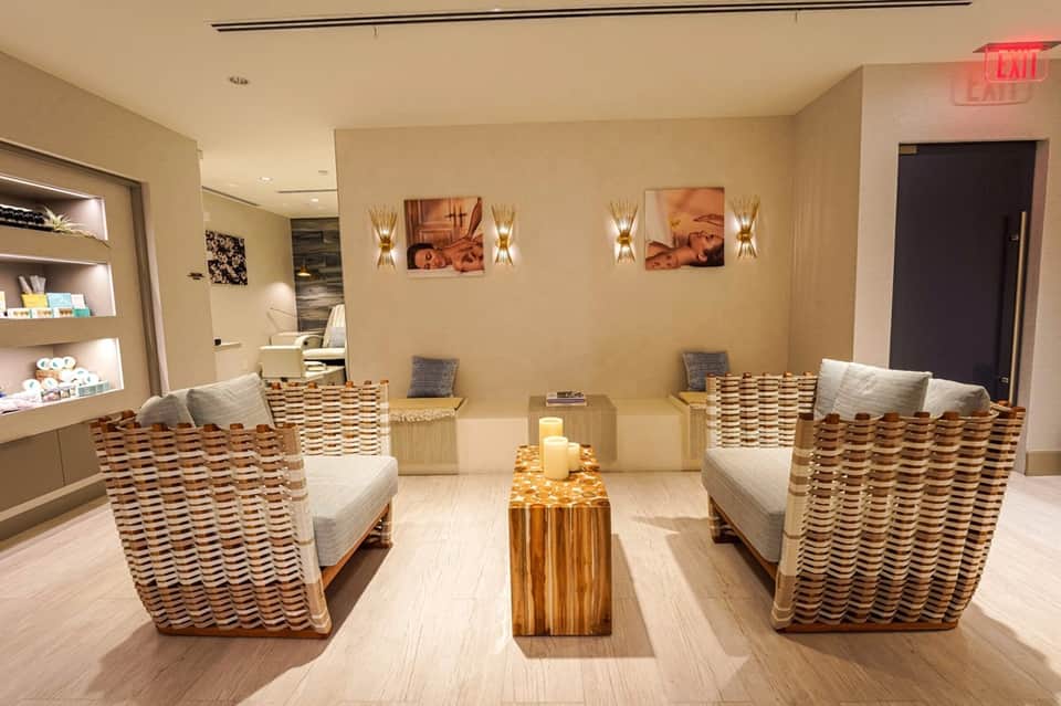 Spa waiting area with woven chairs, warm lighting, and retail shelving
