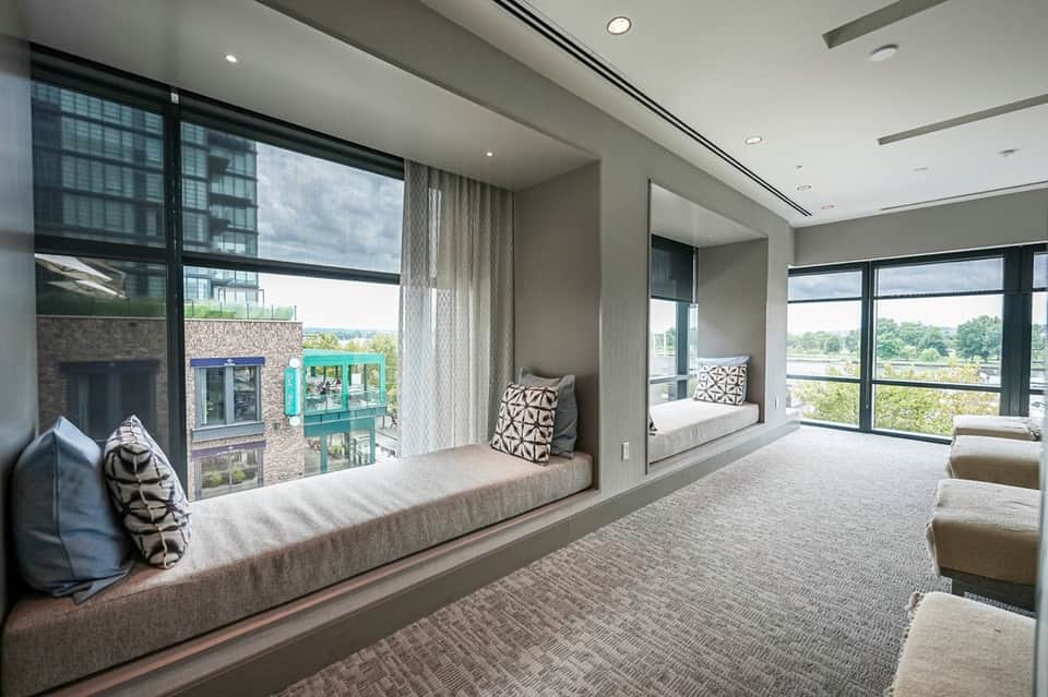Luxury suite with floor-to-ceiling windows, dual window seats, modern furnishings, and panoramic landscape views