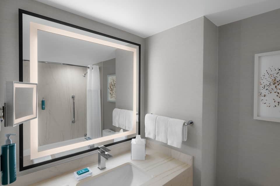 Modern bathroom with illuminated mirror, walk-in shower, and marble finishes
