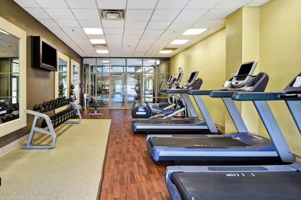 Fitness center with yellow walls, treadmills, exercise equipment, ocean view, and TV monitors